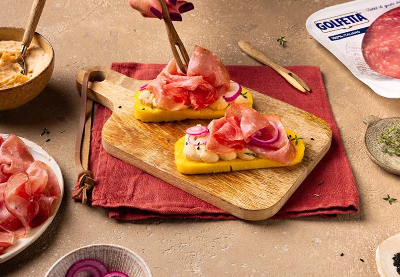 Crostoni di polenta con crema di cannellini, Golfetta e cipolla agrodolce su tagliere